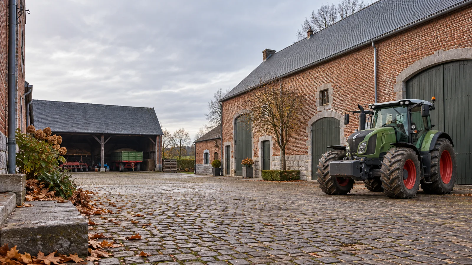 Tracteur garé dans la cour pavée d'une ferme en briques